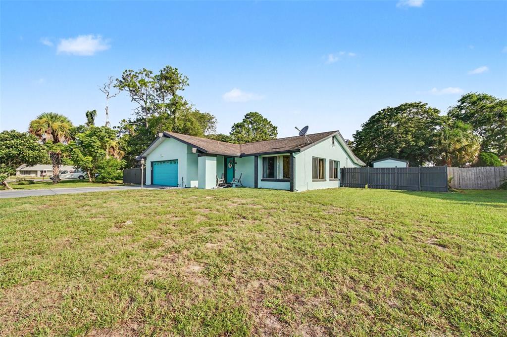 A light green single-story house with a blue garage door sits on a grassy lot — 3 CLARK LANE, PALM COAST, FL