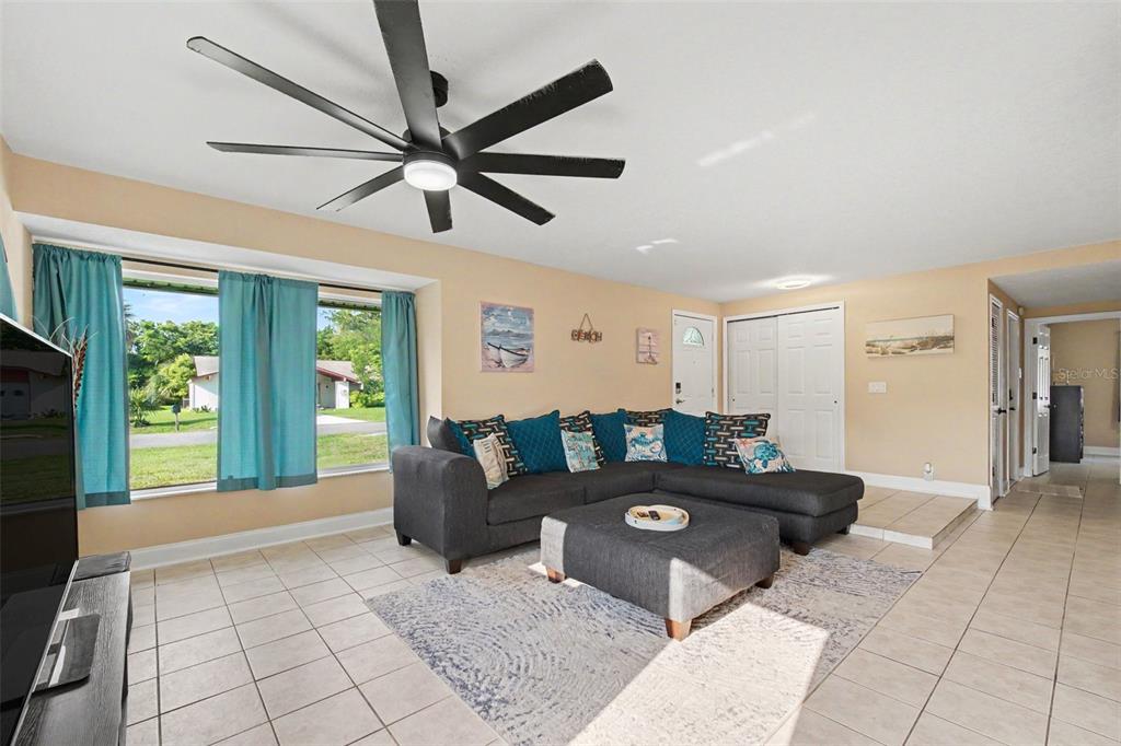 A living room features a large gray sectional sofa, a ceiling fan, and tile flooring — 3 CLARK LANE, PALM COAST, FL