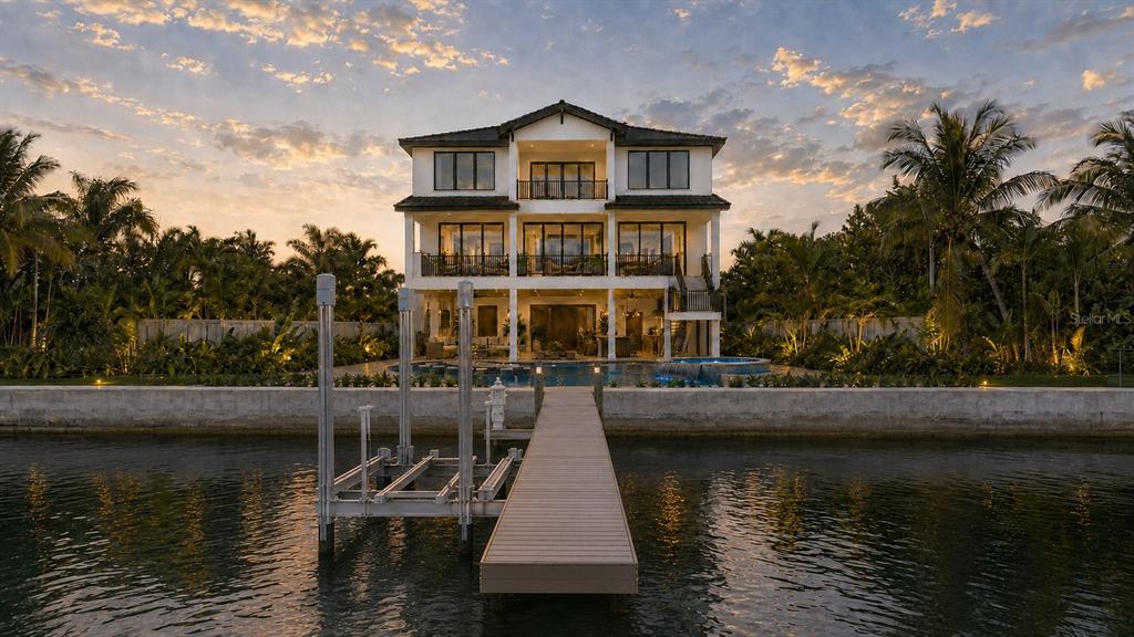An aerial view of a three-story waterfront home with a pool, dock, and patio — 11245 9TH STREET E, TREASURE ISLAND, FL