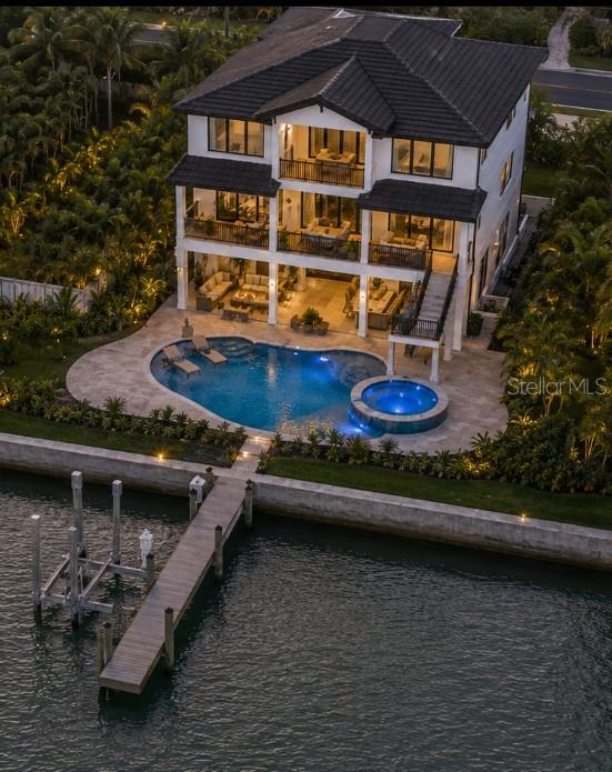 This image shows a custom swimming pool and spa with travertine decking and bar seating — 11245 9TH STREET E, TREASURE ISLAND, FL