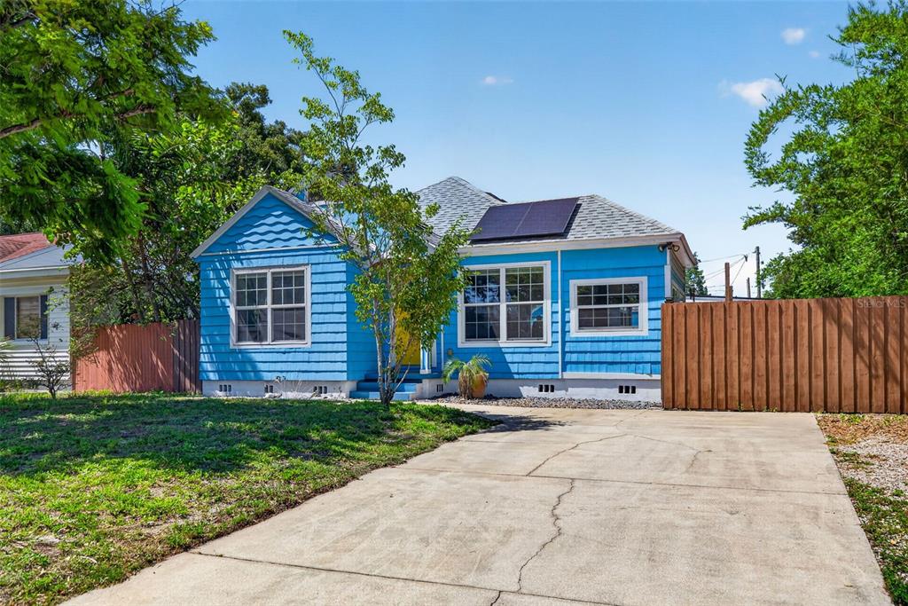 A bright blue house with a concrete driveway and solar panels on the roof — 2101 20TH AVENUE N, ST PETERSBURG, FL