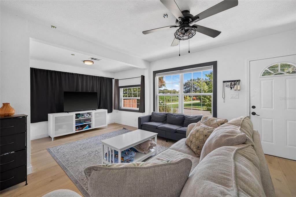 A living room with a gray sofa, television, and an open-concept kitchen in the background — 2101 20TH AVENUE N, ST PETERSBURG, FL