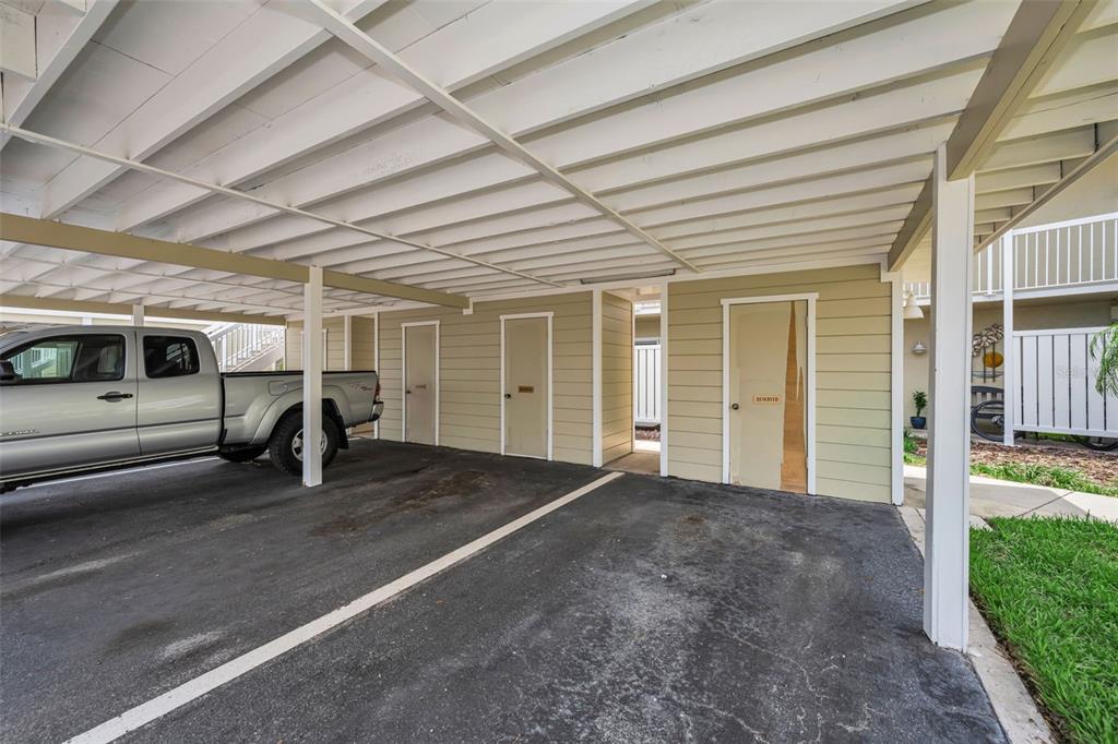 A covered parking area features a silver pickup truck and three storage closet doors — 433 S PAULA DRIVE UNIT 32, DUNEDIN, FL