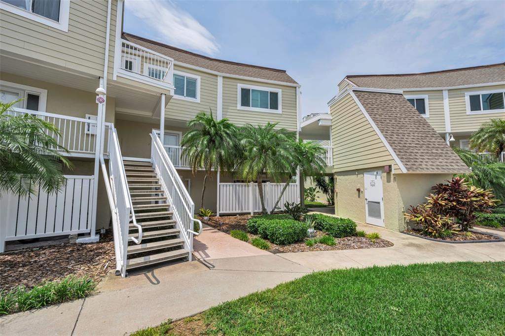 Exterior view of a multi-story apartment building with stairs leading to an upper balcony — 433 S PAULA DRIVE UNIT 32, DUNEDIN, FL