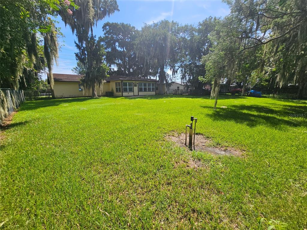 A large grassy backyard features a single-story house and several mature trees with hanging moss — 1292 E LAKE SHORE BOULEVARD, KISSIMMEE, FL