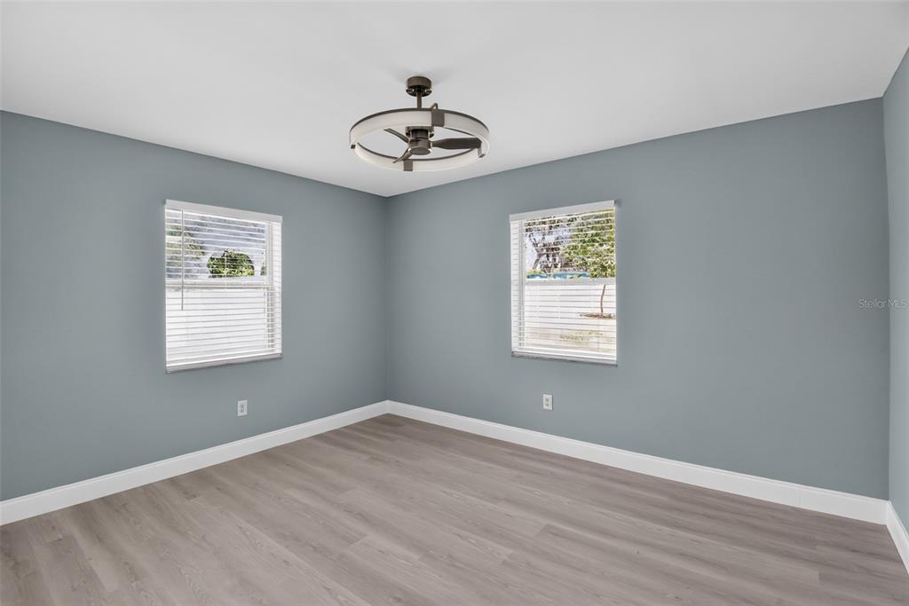 A bedroom with gray walls, light wood-look flooring, white trim, and multiple white closet doors — 1148 FOUNTAINHEAD DRIVE, DELTONA, FL