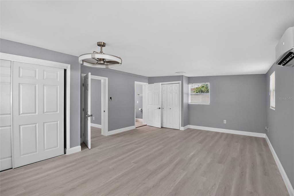 An empty bedroom with gray walls, light wood-look flooring, two windows, and a ceiling fan — 1148 FOUNTAINHEAD DRIVE, DELTONA, FL