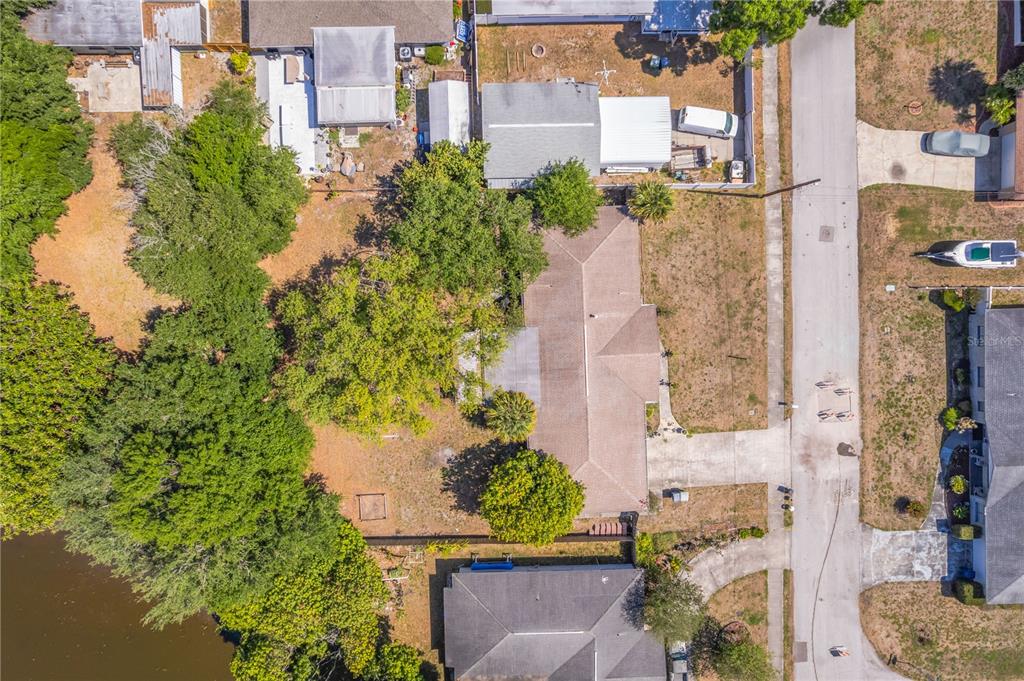 An aerial view shows a house with a large yard, mature trees, and a nearby pond — 5007 S HESPERIDES STREET, TAMPA, FL