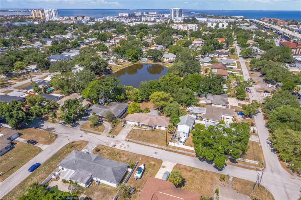 An aerial view shows a residential neighborhood with a central pond and nearby coastal buildings — 5007 S HESPERIDES STREET, TAMPA, FL
