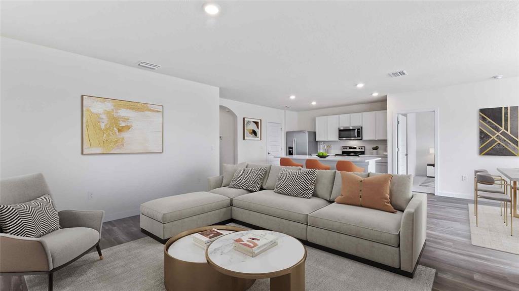 A living room with a sectional sofa, coffee table, and an open kitchen in the background — 11975 FALLOW DOWN DRIVE, DADE CITY, FL
