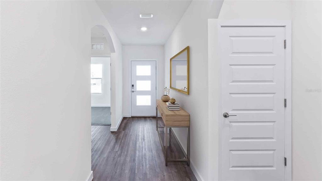 A bright entryway features wood-look flooring, a white front door, and a console table — 11975 FALLOW DOWN DRIVE, DADE CITY, FL
