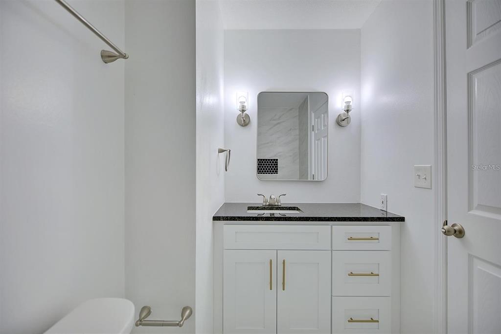 A bathroom features a white vanity with gold hardware, a dark countertop, and a mirror — 503 RICH STREET, AVON PARK, FL