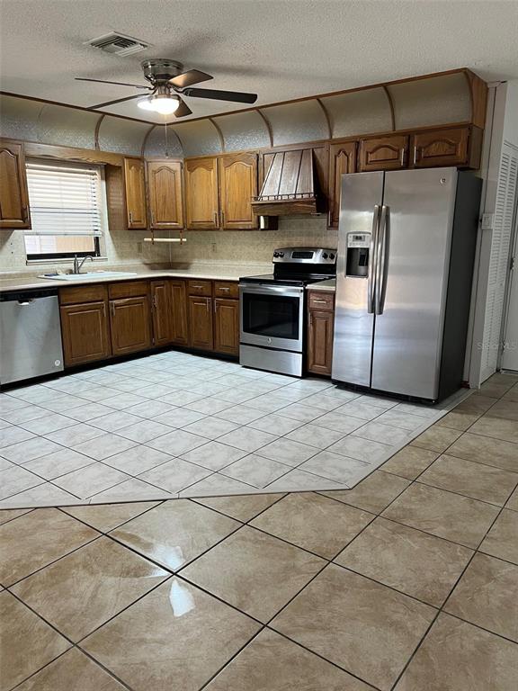 A kitchen features wood cabinets, stainless steel appliances, and two different types of floor tiles — 29 MIAMI DRIVE, LAKE PLACID, FL