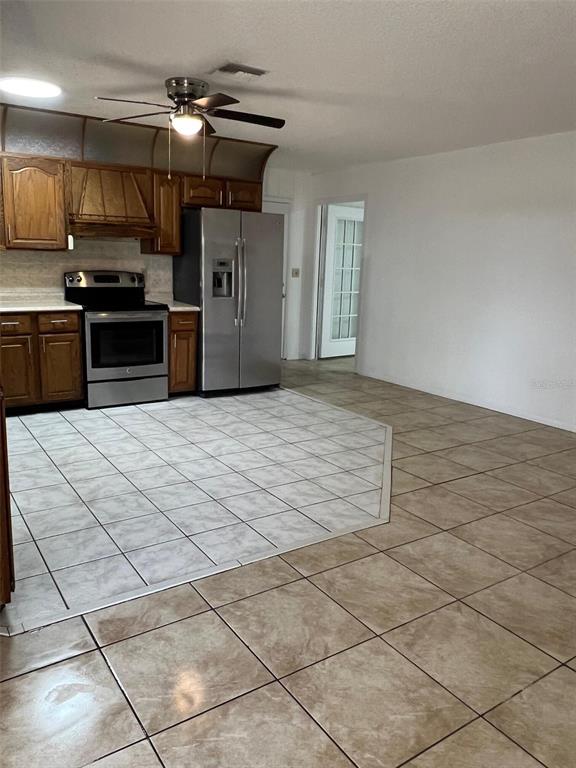 A kitchen features wood cabinets, stainless steel appliances, and a tiled floor with two patterns — 29 MIAMI DRIVE, LAKE PLACID, FL