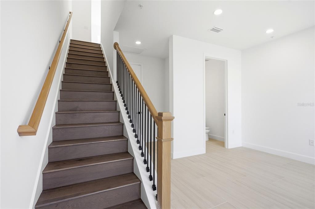 A staircase with dark wood treads and a black metal railing leads to an upper level — 2130 WHITNEY MARSH ALLEY, ORLANDO, FL