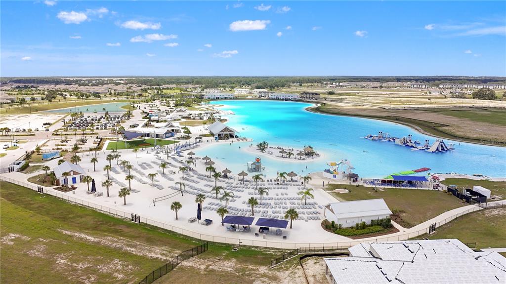 An aerial view shows a large man-made turquoise lagoon with sandy beaches and water slides — 10149 TRUMPET HONEYSUCKLE WAY, SAN ANTONIO, FL