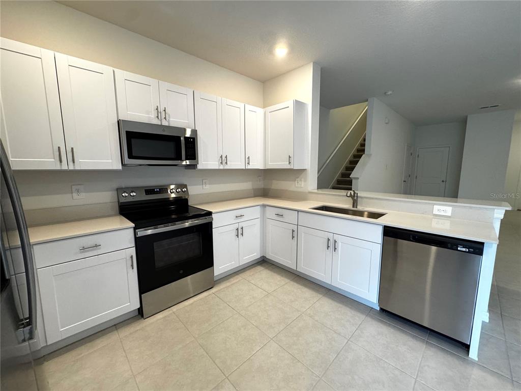 A kitchen features white cabinets, stainless steel appliances, and light-colored countertops — 10149 TRUMPET HONEYSUCKLE WAY, SAN ANTONIO, FL