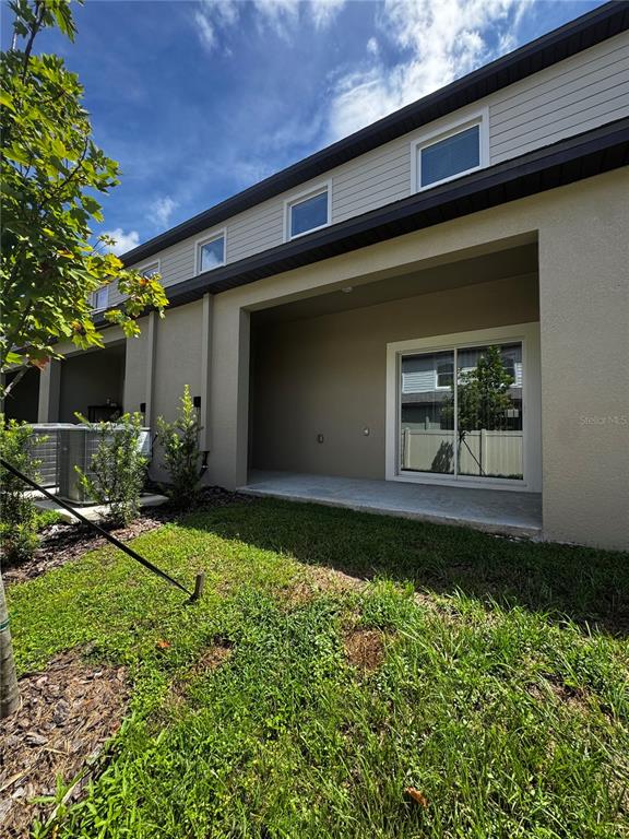 The exterior of a two-story home features a covered patio and a small grassy yard — 10149 TRUMPET HONEYSUCKLE WAY, SAN ANTONIO, FL