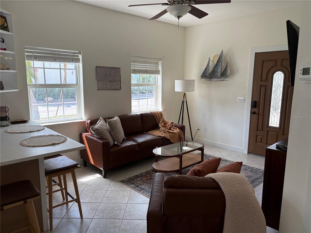 A living room features a brown leather sofa, a glass coffee table, and tile flooring — 101 E BAY DRIVE, TREASURE ISLAND, FL