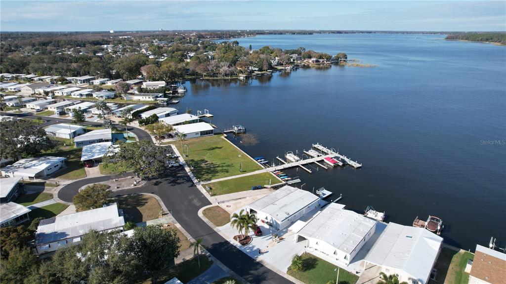 An aerial view shows a waterfront community with mobile homes, a boat dock, and a lake — 183 PHILADELPHIA BOULEVARD UNIT 22, PALM HARBOR, FL