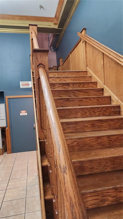 A wooden staircase with a matching handrail ascends against a blue wall — 101 W OAK STREET UNIT 101, ARCADIA, FL
