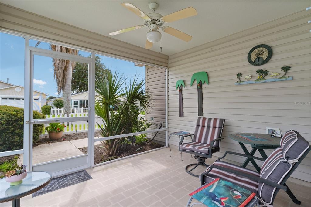 A screened-in porch features a ceiling fan, tiled flooring, outdoor furniture, and a view of a neighborhood — 17362 SE 78TH HARMONY CIRCLE, THE VILLAGES, FL