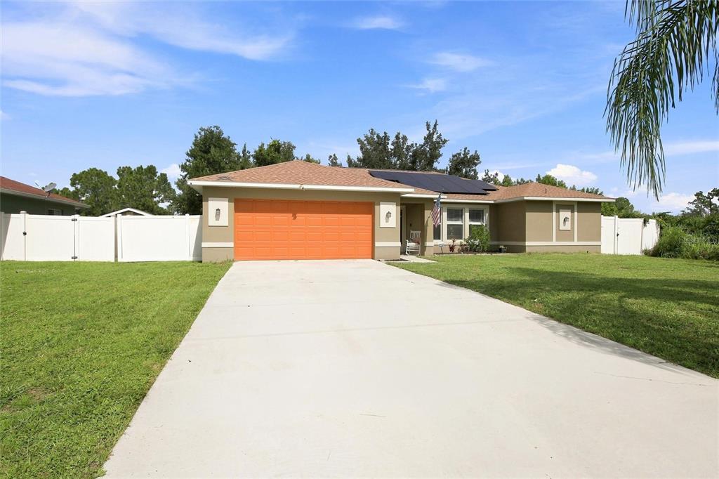 A single-story house with a bright orange garage door, tan exterior, and a concrete driveway — 2583 PENNSYLVANIA TERRACE, NORTH PORT, FL
