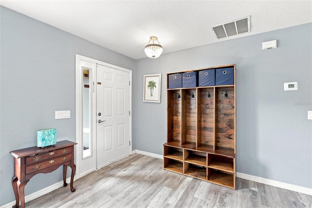 An entryway features light blue walls, wood-look flooring, a wooden coat rack, and a console table — 2583 PENNSYLVANIA TERRACE, NORTH PORT, FL