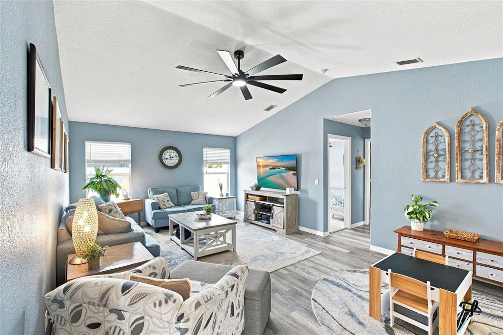 A living room features light blue walls, a vaulted ceiling with a fan, and wood-look flooring — 2583 PENNSYLVANIA TERRACE, NORTH PORT, FL