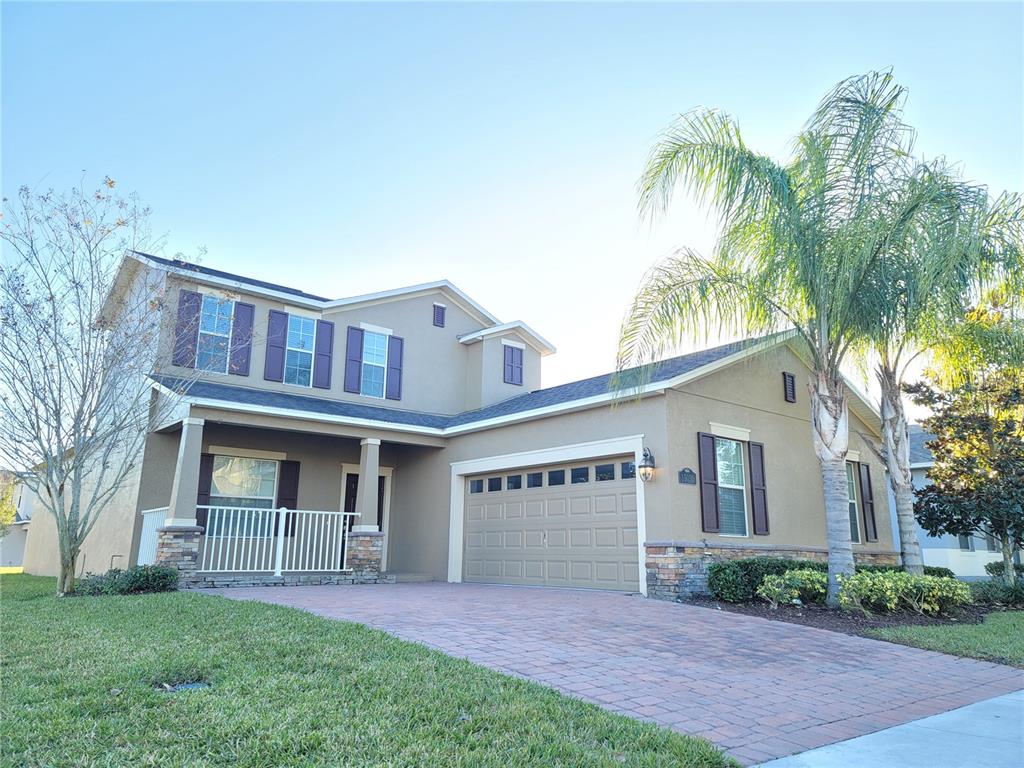 A two-story suburban house features a brick driveway, a garage, and a palm tree — 15030 EVERGREEN OAK LOOP, WINTER GARDEN, FL