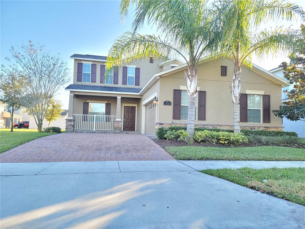 A two-story suburban house with a brick paver driveway, palm trees, and brown shutters — 15030 EVERGREEN OAK LOOP, WINTER GARDEN, FL