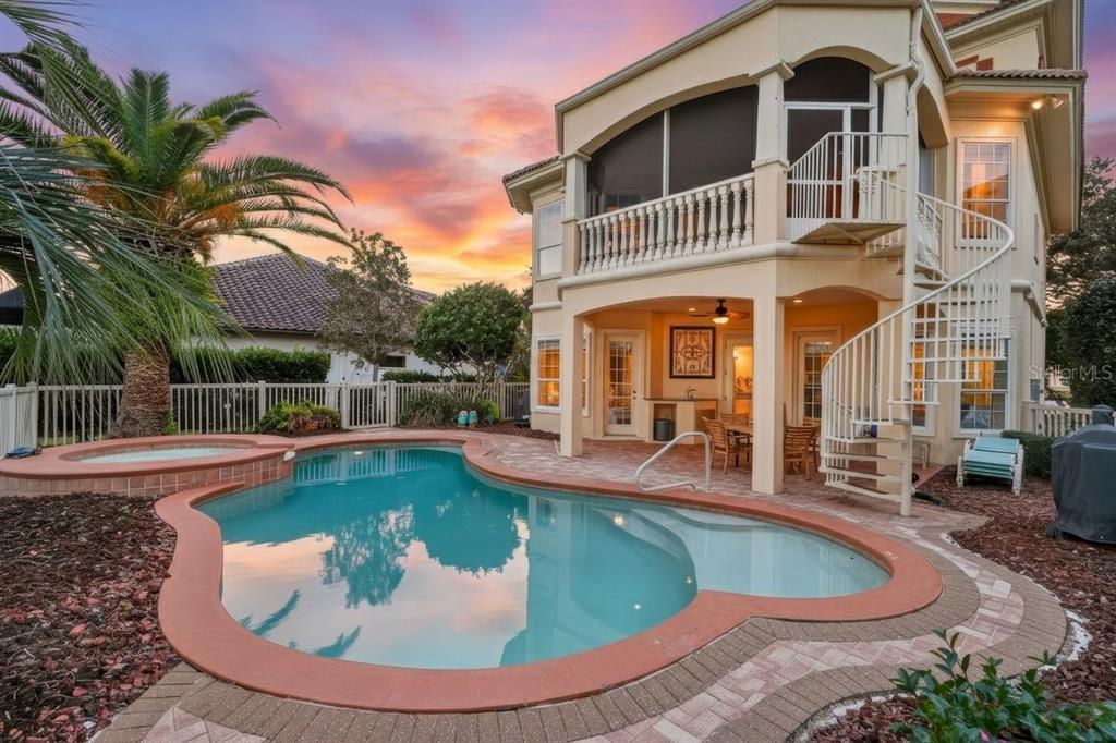 A two-story house with a pool, spa, and spiral staircase at sunset — 29 OAK VIEW CIRCLE E, PALM COAST, FL