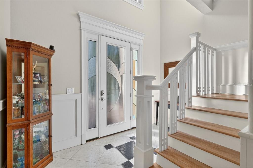 An entryway features a glass-paneled front door, a wooden display cabinet, and a staircase — 29 OAK VIEW CIRCLE E, PALM COAST, FL
