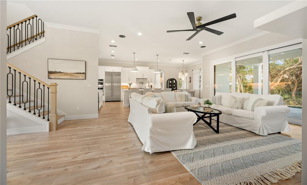 An open-concept living room with white sofas, a patterned rug, and a staircase — 2549 PALM AVENUE, FLAGLER BEACH, FL