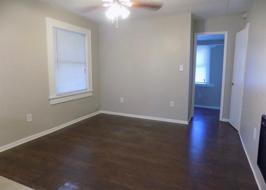 An empty room with gray walls, dark wood-look flooring, a ceiling fan, and a window — 626 HIGHLAND STREET N, ST PETERSBURG, FL