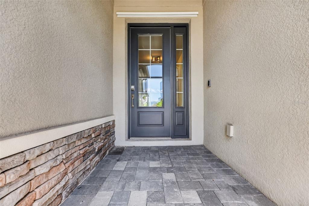 A front entryway features a dark gray door with glass panels and stone siding — 4881 SEAFOAM TRAIL, BRADENTON, FL