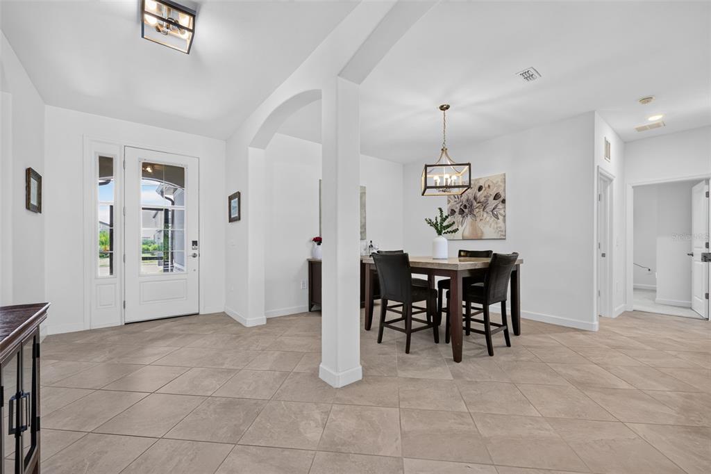 A bright entryway with tile flooring leads into a dining area featuring a modern chandelier — 4881 SEAFOAM TRAIL, BRADENTON, FL