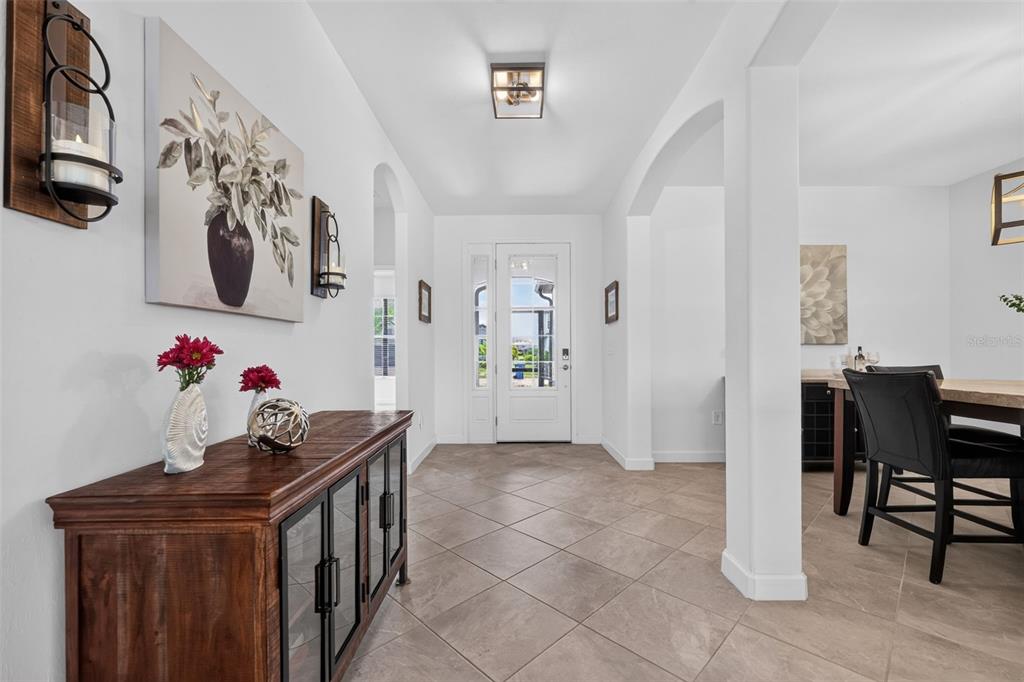 A tiled entryway features a wooden console table, wall art, and a glass-paneled front door — 4881 SEAFOAM TRAIL, BRADENTON, FL
