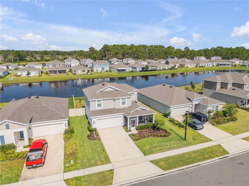 An aerial view shows suburban houses with driveways and a pond in a residential neighborhood — 3986 WILLOWBROOK DRIVE, EDGEWATER, FL