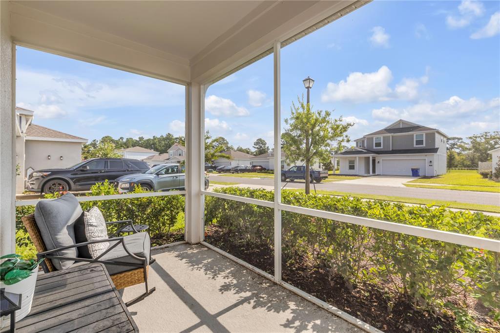 A screened-in porch overlooks a suburban street with houses, parked cars, and a small tree — 3986 WILLOWBROOK DRIVE, EDGEWATER, FL