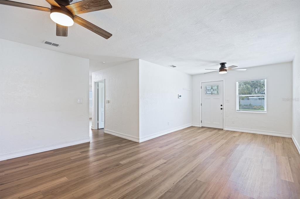 A bright living room features white walls, wood-look flooring, and two ceiling fans — 4006 S SHAMROCK ROAD, TAMPA, FL