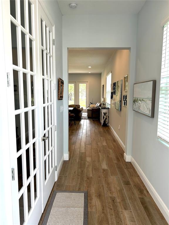 A hallway with wood-look tile flooring leads to a living area with French doors — 2042 KEY BAY TRAIL, KISSIMMEE, FL