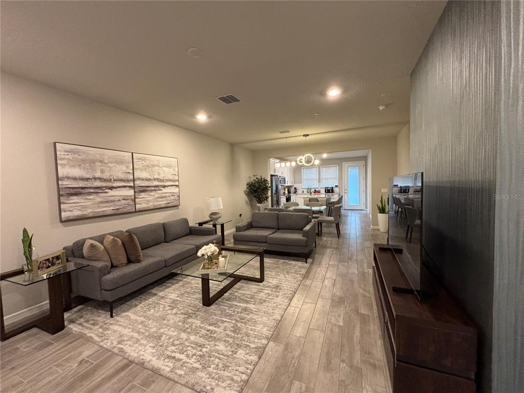 A living room features gray sofas, a glass coffee table, and wood-look tile flooring — 14550 ORCHID ISLAND DRIVE, ORLANDO, FL