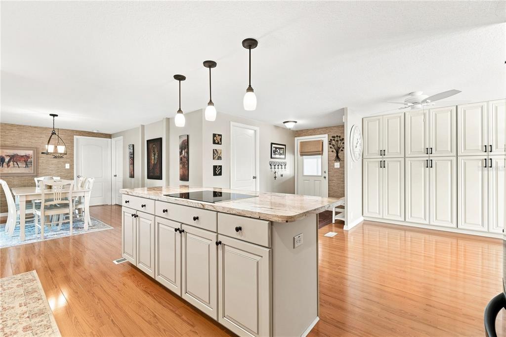 A kitchen features a large island with a stone countertop, pendant lights, and light cabinetry — 8241 WEATHERFORD AVENUE, BROOKSVILLE, FL