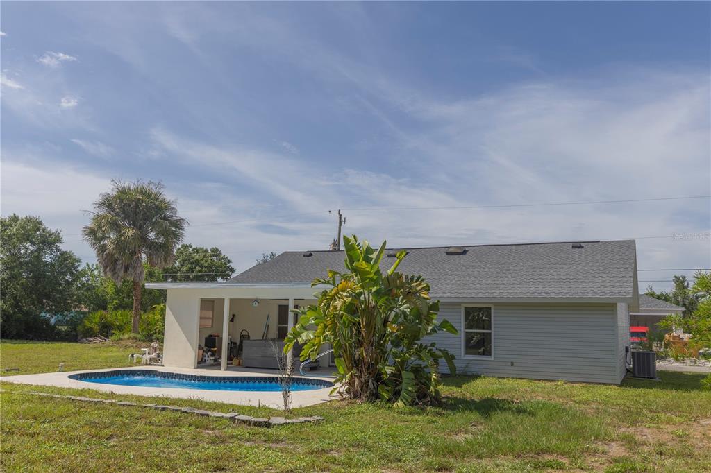 A backyard view of a house with a swimming pool, covered patio, and palm tree — 10453 GREENWAY AVENUE, ENGLEWOOD, FL
