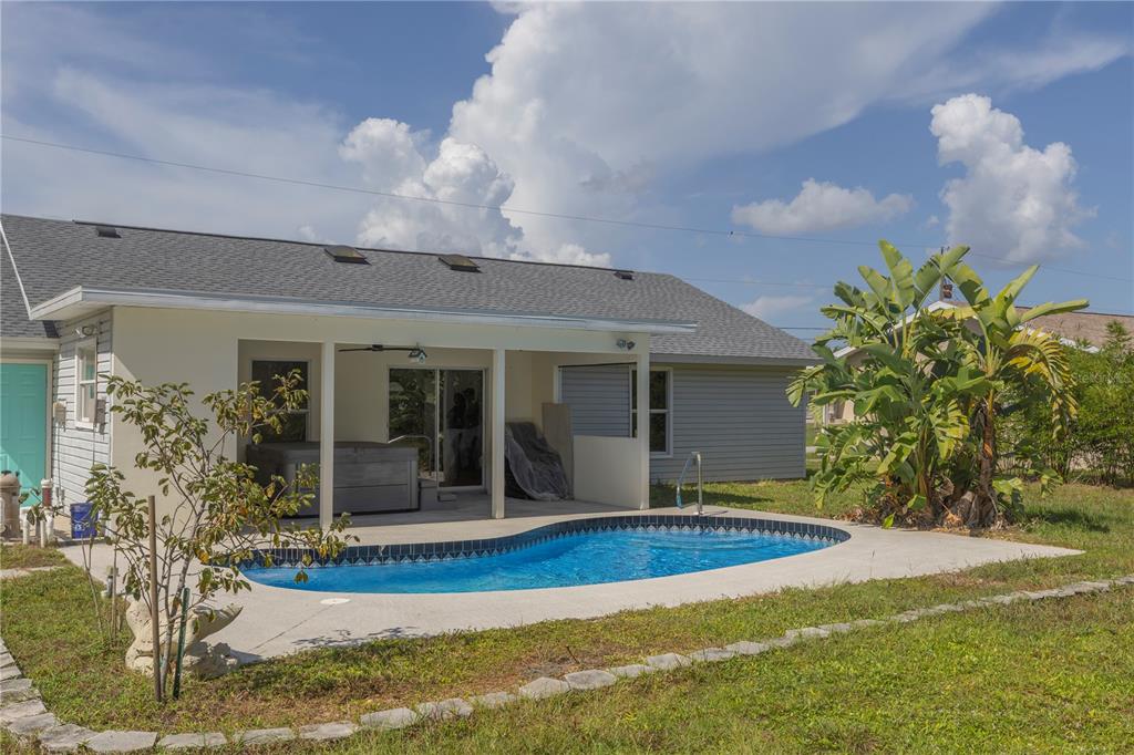 A backyard features a kidney-shaped swimming pool, a covered patio with a hot tub, and landscaping — 10453 GREENWAY AVENUE, ENGLEWOOD, FL