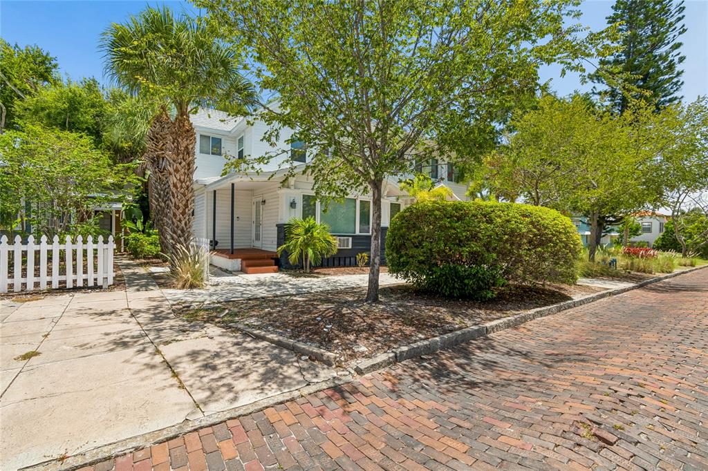 A two-story house with white siding, a dark stone base, and palm trees in front — 255 6TH AVENUE N, ST PETERSBURG, FL