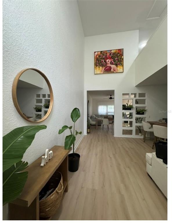 An entryway with a wood console table, round mirror, and open shelving leading to a living area — 16320 PARKSTONE PALMS COURT, TAMPA, FL