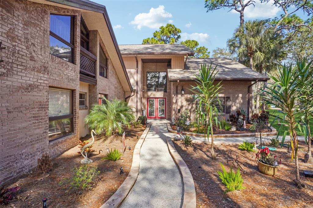 A brick house with a paved walkway leading to a red double-door entrance — 29207 OLD MILL W, TAVARES, FL