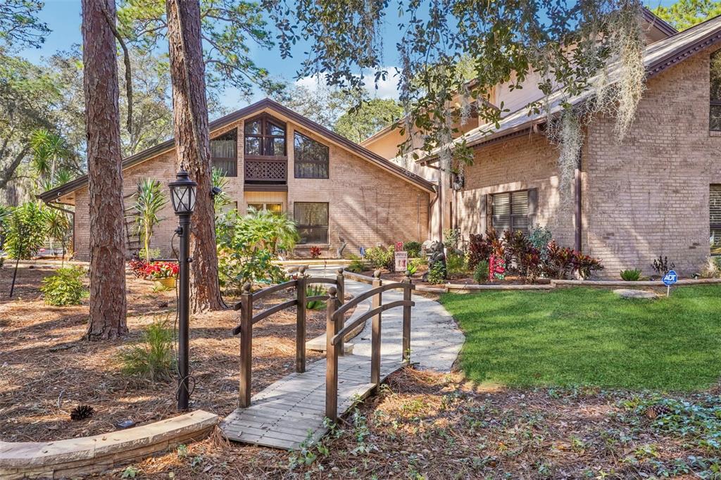A brick house with a wooden footbridge leading to the front entrance through a yard — 29207 OLD MILL W, TAVARES, FL